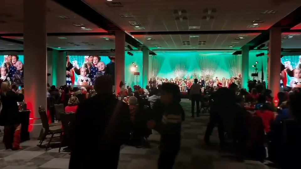 Ballroom gala with teal wash lighting and a full room of guests