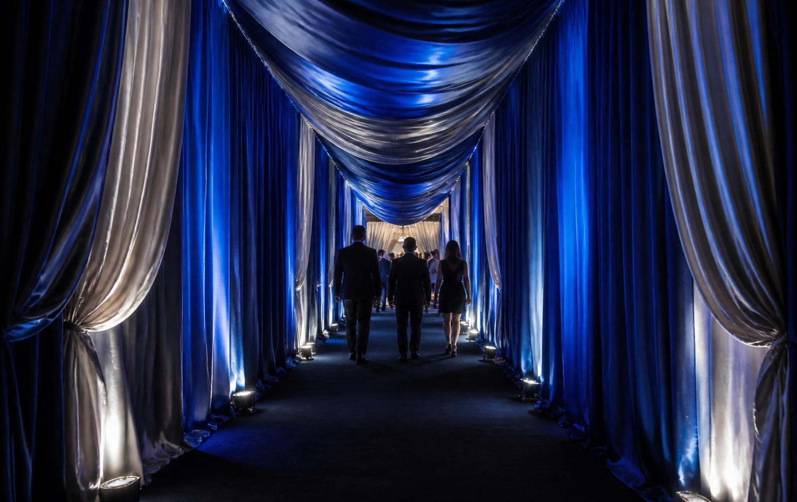 Draped entry tunnel in deep blue and silver fabric at a corporate activation