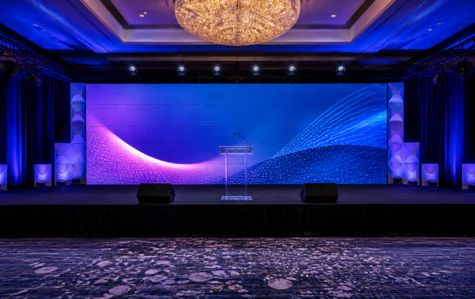 Corporate stage with a wide LED video wall, podium, monitors and architectural lighting